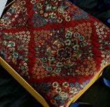 Close-up of a red patterned rug with intricate designs on a dark background