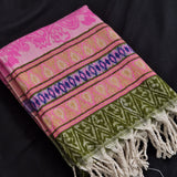 A folded woven textile with fringe, featuring pink, olive green, purple, and beige geometric and floral patterns on a black fabric background.