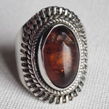 A vintage handcrafted amber 925 silver sterling ring with a detailed and ornate band, featuring a large amber gemstone in the center.