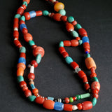 A multicolored beaded necklace with a variety of geometric shaped beads, featuring colors such as red, blue, green, and beige.