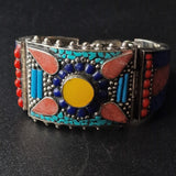 A colorful Tibetan style bracelet featuring silver, turquoise, coral, and lapis, with a vintage design and handmade appearance.