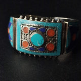 A Mantra Tibetan Turquoise Bracelet with silver and turquoise colors, featuring a vintage design with inlaid stones and decorative patterns.